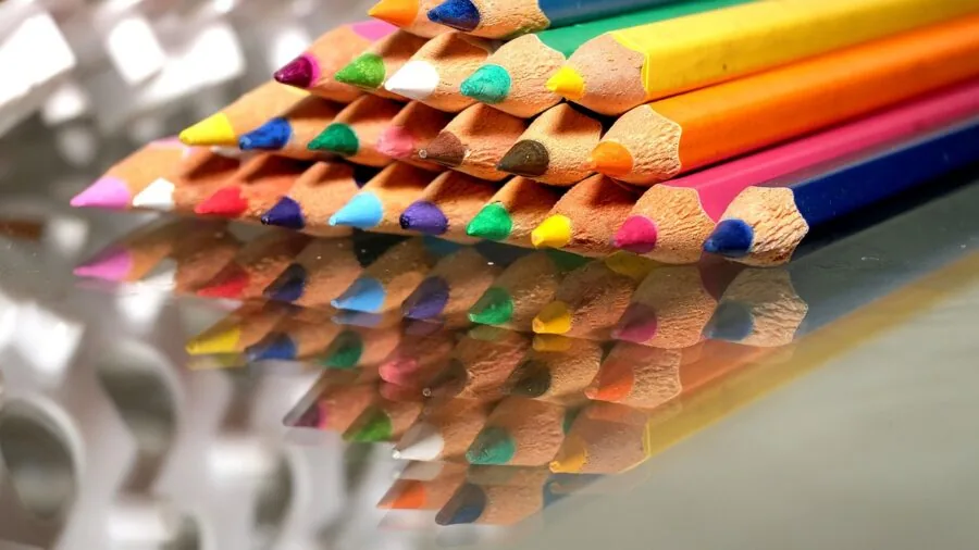 Young child arranging and organizing colorful art supplies and markers on a table