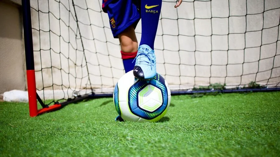 Young child assembling a foldable soccer net on grass for backyard practice