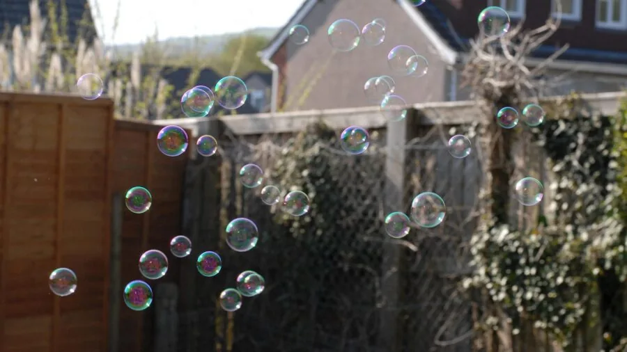 Young child blowing bubbles outdoors on a sunny day, experiencing wonder and joy
