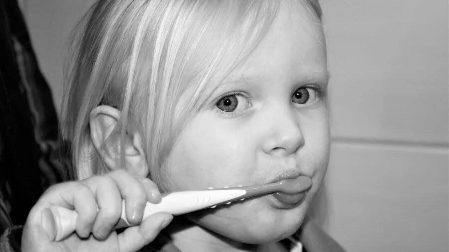 Young child brushing teeth at bathroom sink during daily morning hygiene routine