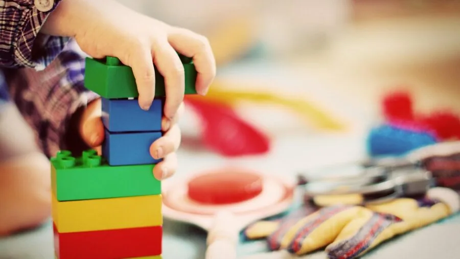 Young child building with large colorful construction blocks on wooden floor
