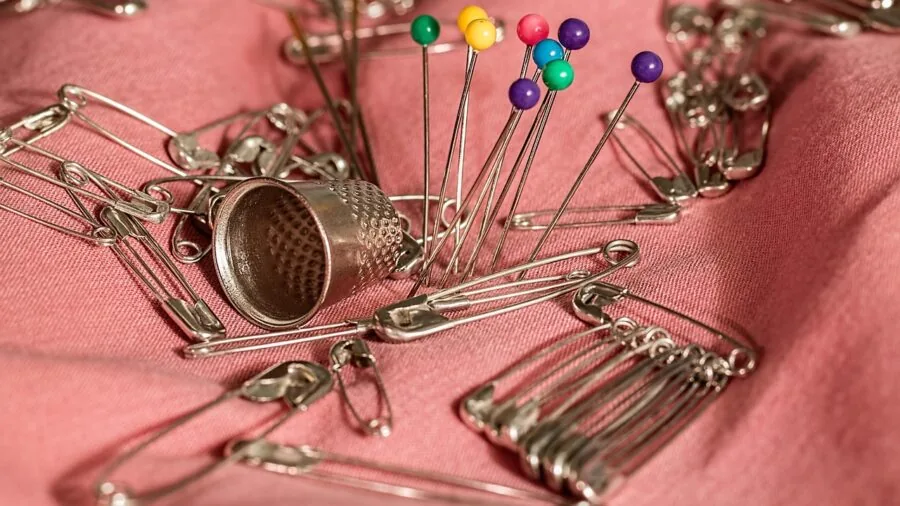 Young child carefully threading a needle while learning to sew with adult supervision and proper tools