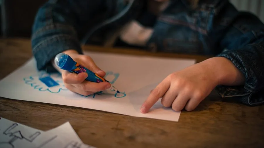 Young child coloring with markers at a table, focused on creative artwork
