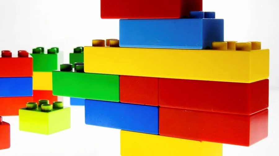 Young child concentrating while assembling colorful building blocks with small pieces on wooden table