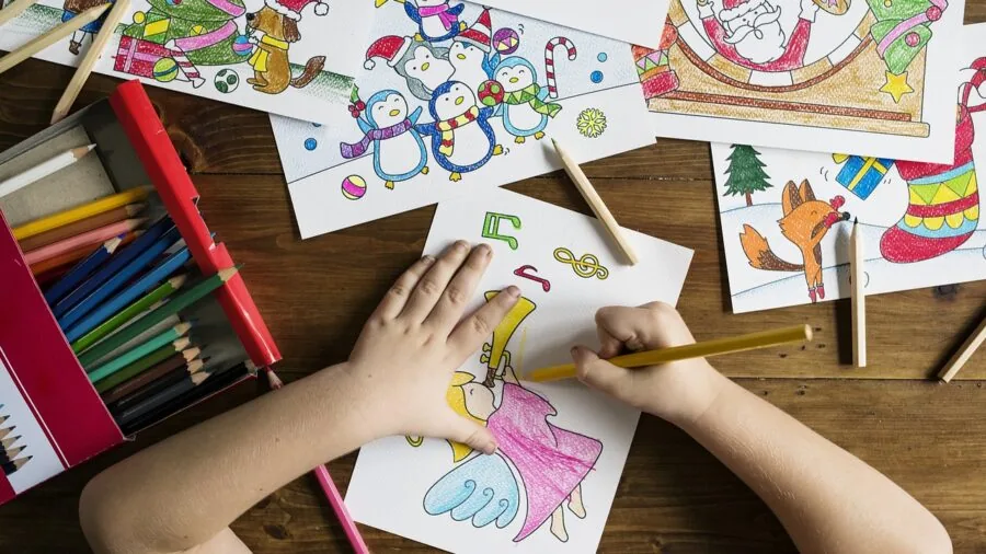 Young child concentrating while coloring with large crayons on paper at a table