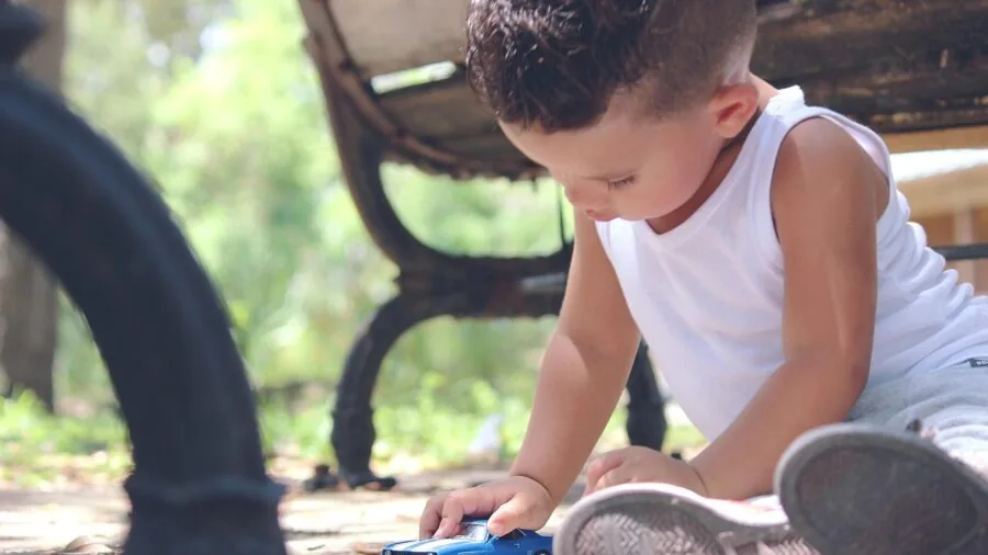 Young child engaged in a game while traveling in a car, looking out the window during family road trip