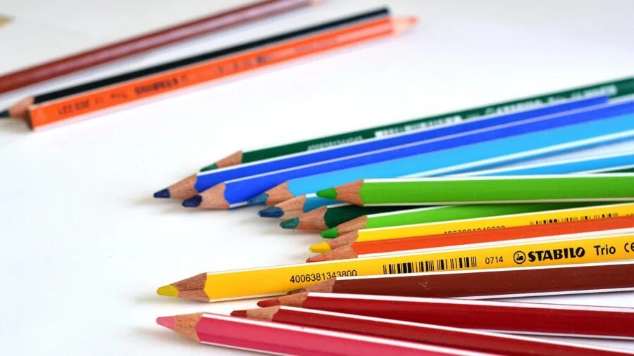 Young child engaged in creative drawing activity with colorful crayons at a table, demonstrating safe art play