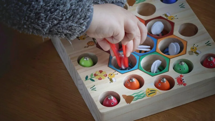 Young child engaged in hands-on play with wooden toys, exploring tactile learning without screens
