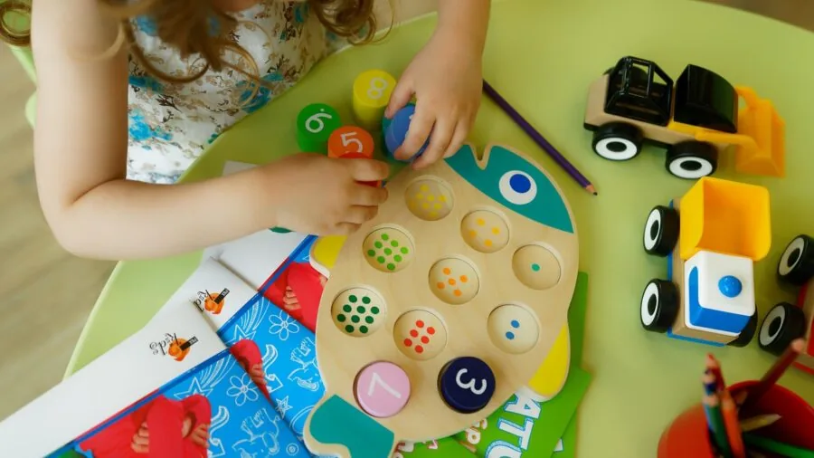 Young child engaged in imaginative play with a toy truck on wooden floor indoors