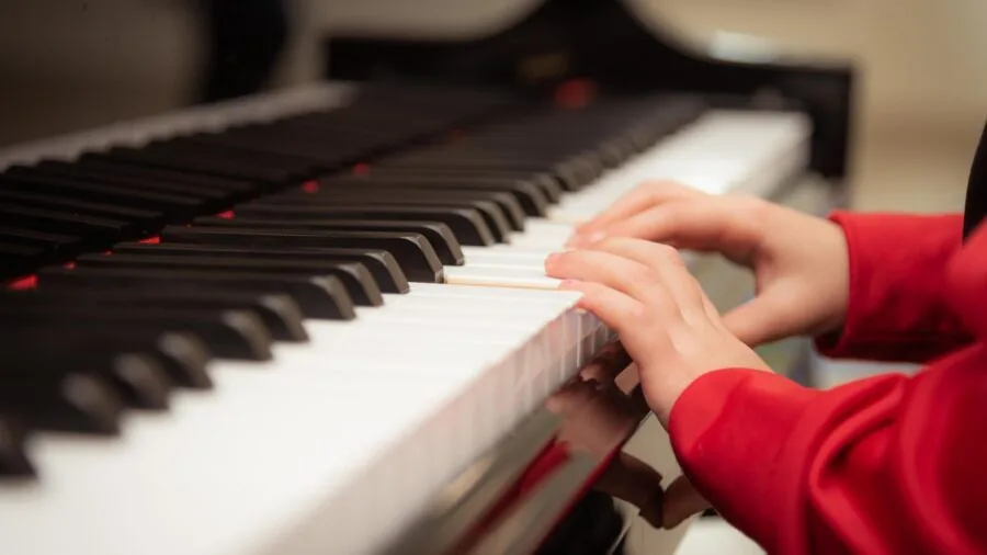 Young child engaged in musical learning, playing a xylophone with focused concentration and joy