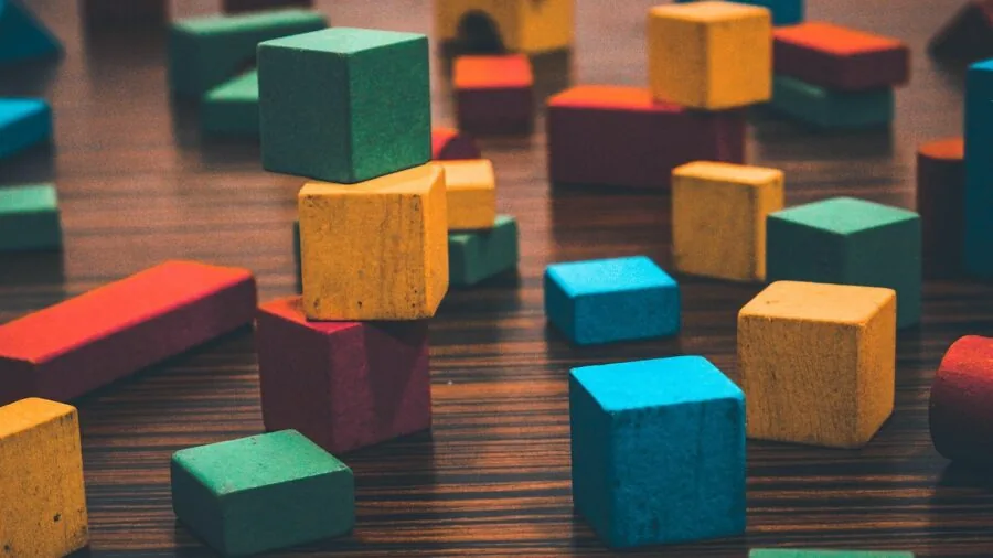 Young child engaged in open-ended block building play with colorful construction pieces on floor
