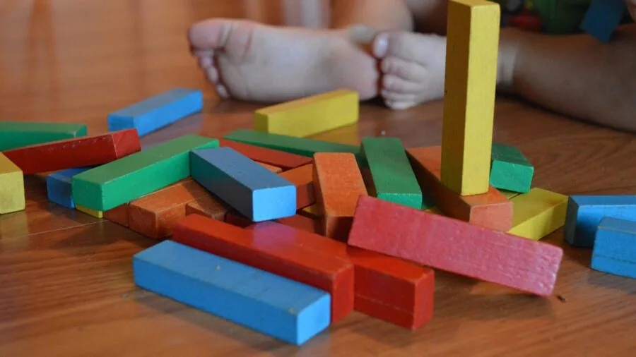 Young child engaged with colorful building blocks and coding toys on wooden floor