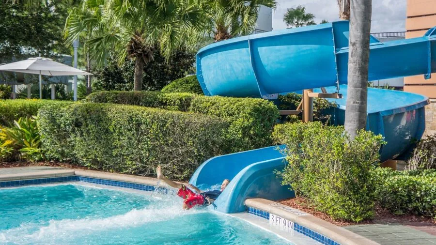 Young child enjoying a colorful water slide on a sunny summer day in a backyard setting