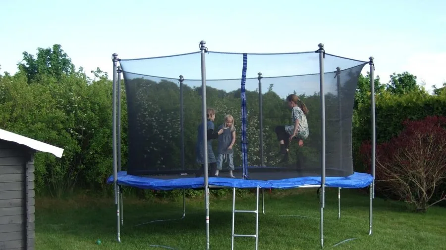Young child enjoying outdoor trampoline play with safety net enclosure visible