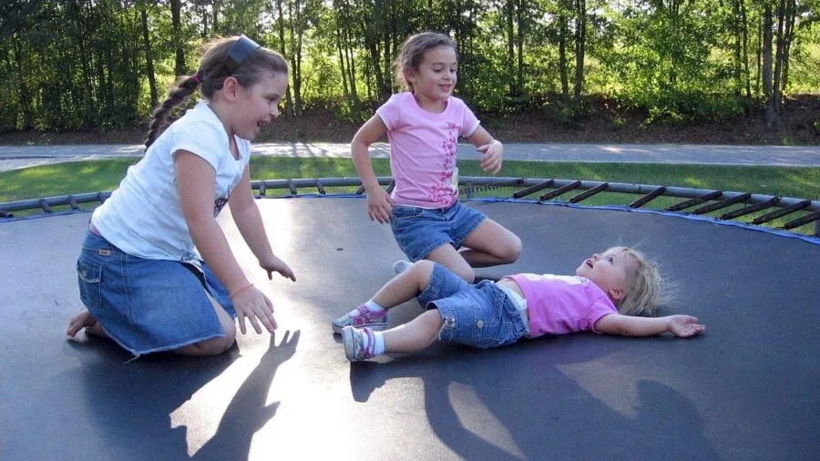 Young child enjoying safe trampoline play with protective netting enclosure in backyard