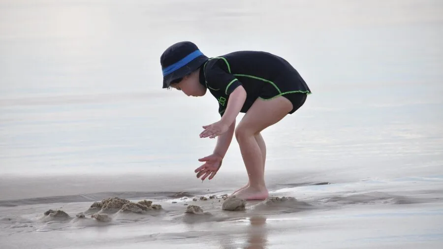 Young child enjoying time in shallow ocean water at beach during sunny day