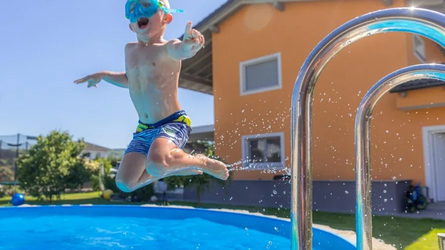 Young child helping to drain water from a backyard kiddie pool during maintenance