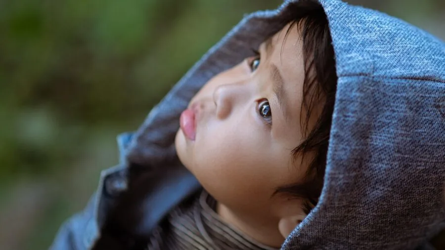 Young child in casual hoodie enjoying active playtime outside in natural daylight