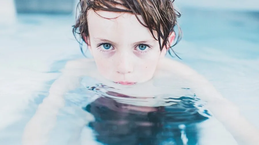 Young child in pool water wearing swim diaper, demonstrating fabric durability in chlorinated environment