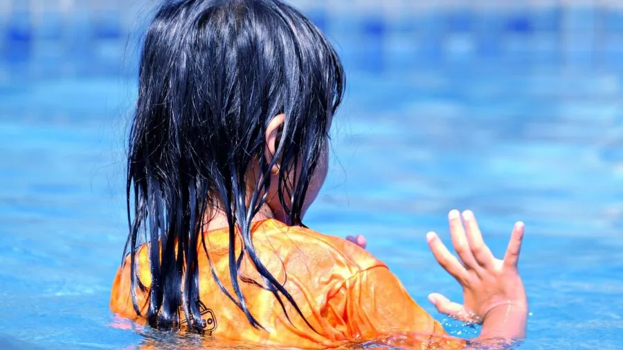 Young child playing in pool water during swimming lesson, lifestyle scene