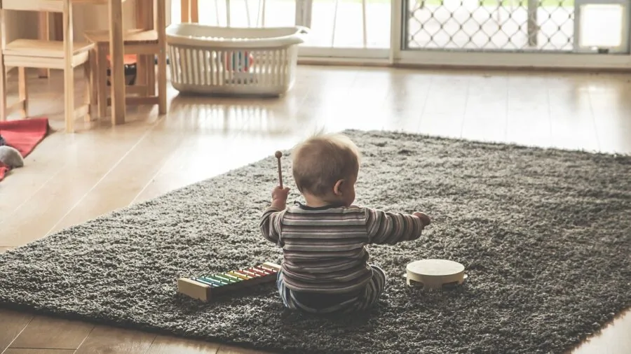 Young child playing safely near stairs with protective gate installed in home entryway