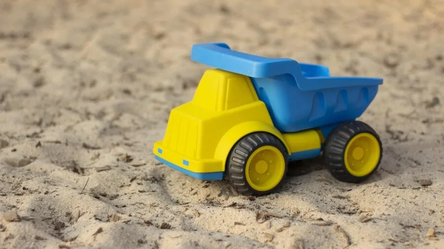 Young child playing with multiple toy trucks on floor, exploring different pieces and sets