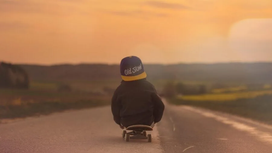 Young child practicing skateboarding on a smooth outdoor surface, learning balance and technique