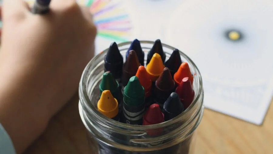Young child reaching for colorful books on shelf, developing organizational skills