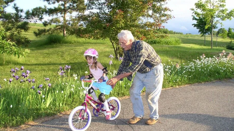 Young child riding balance bike on outdoor path with parent nearby, demonstrating childhood development and outdoor learning