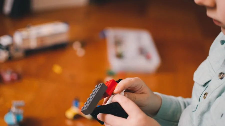 Young child safely playing with large colorful building blocks on floor indoors