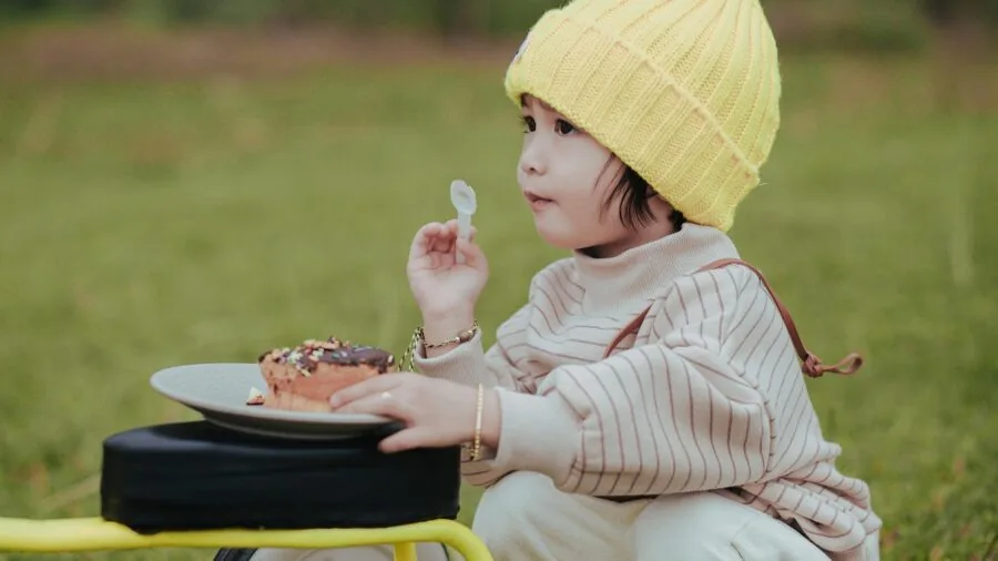 Young child sitting at dining table with correct posture while eating a meal