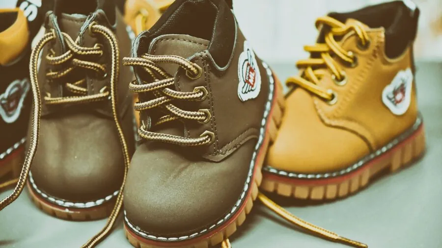Young child sitting down trying on new sneakers with parent helping ensure proper fit and comfort