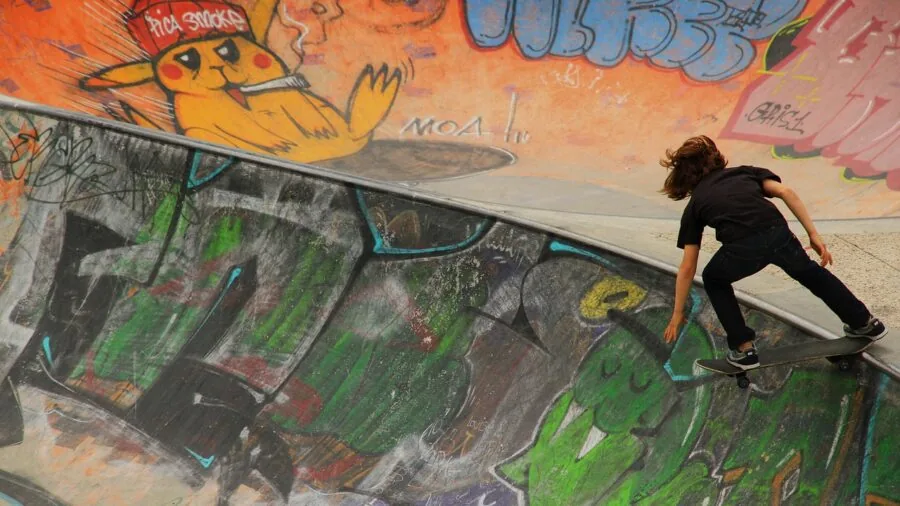 Young child skateboarding outdoors wearing protective gear while playing in natural daylight