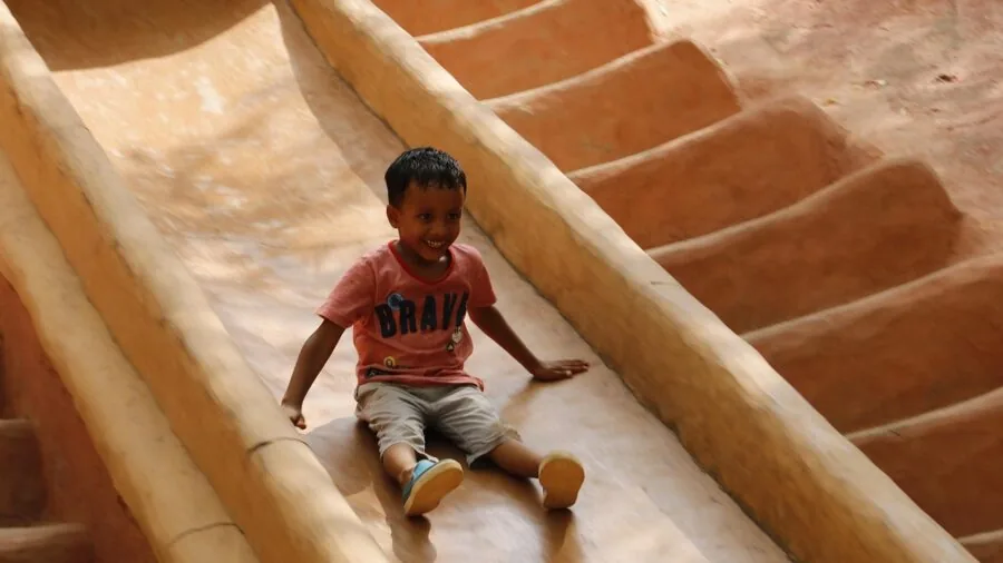 Young child sliding down playground slide outdoors on sunny day