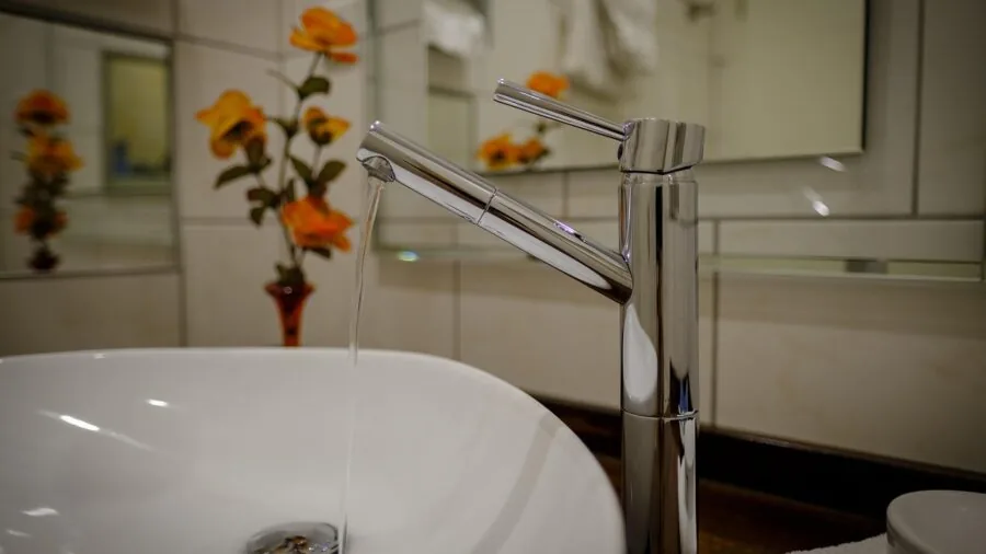 Young child standing on step stool to reach bathroom sink and mirror safely