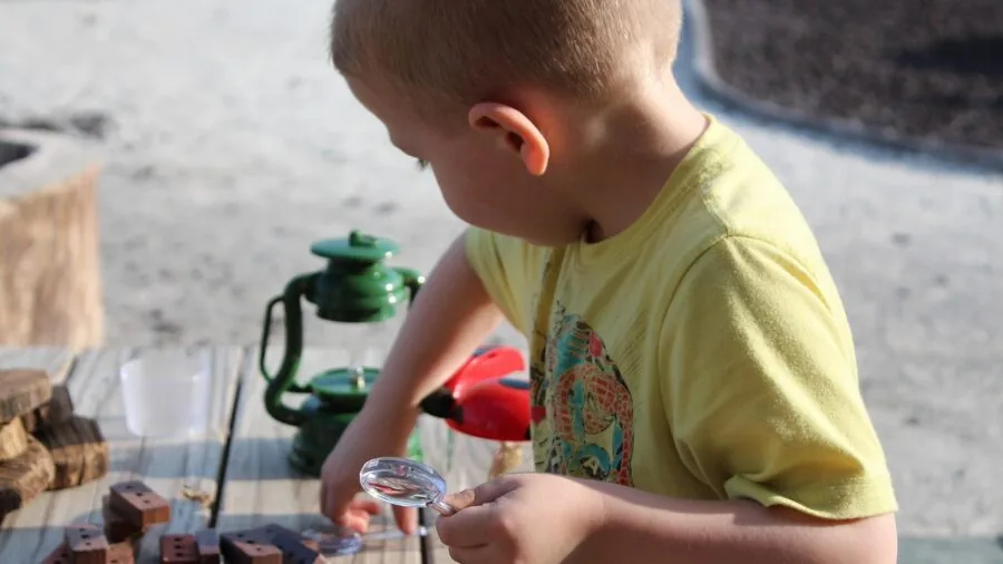 Young child using magnifying glass to examine objects with curiosity and wonder