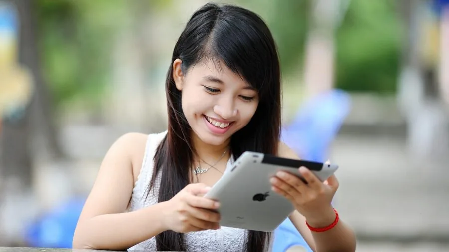 Young child watching tablet screen while seated in car backseat during travel