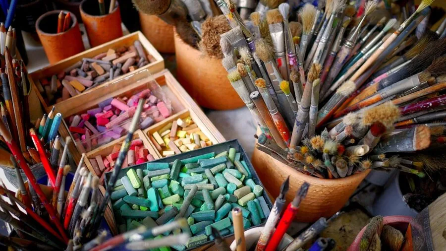 Young child wiping hands and organizing craft materials after a messy art activity