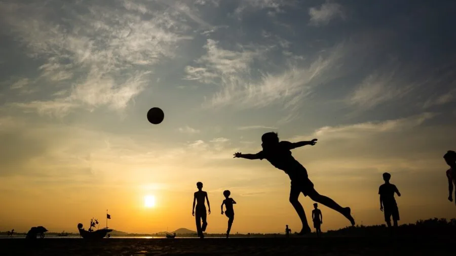 Young children playing soccer on grass field with focus on safe, stable goal setup and active gameplay