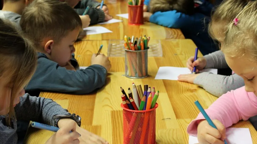 Young child's hand gripping a crayon while drawing on paper