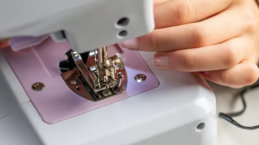 Young child's hands carefully stitching colorful fabric pieces together during a handmade sewing project
