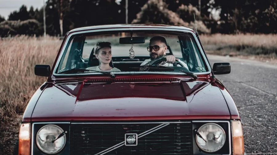Young couple on a road trip inside a car, enjoying travel together during daytime
