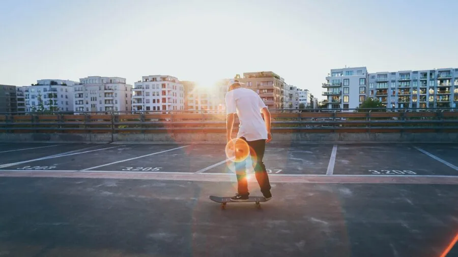 Young skateboarder in protective gear practicing tricks on concrete surface outdoors