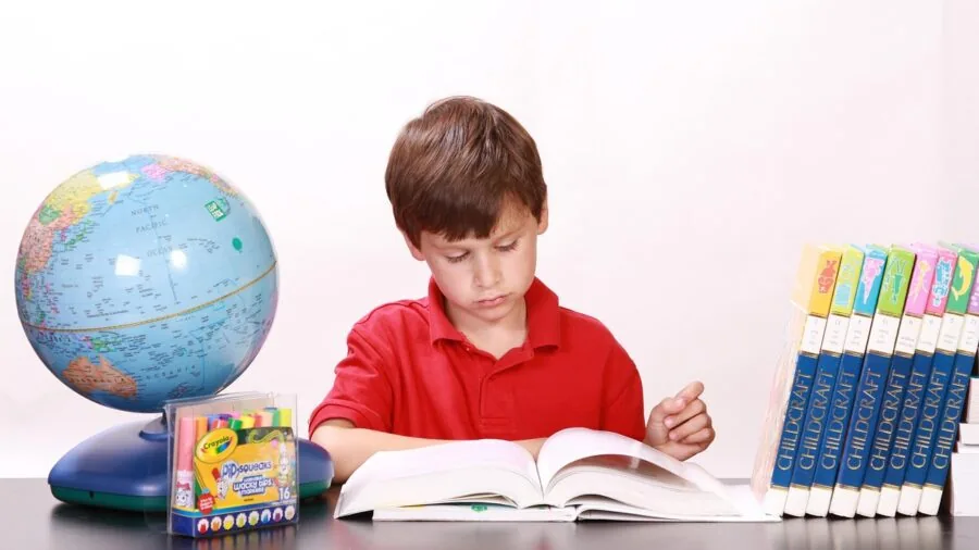 Young student learning with globe on desk in bright home study space