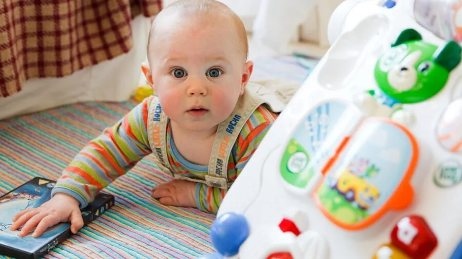 Young toddler climbing on foam blocks inside home playroom