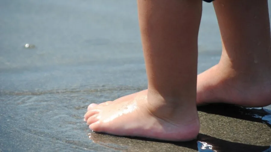 Young toddler playing and splashing in shallow water during summer outdoor activity